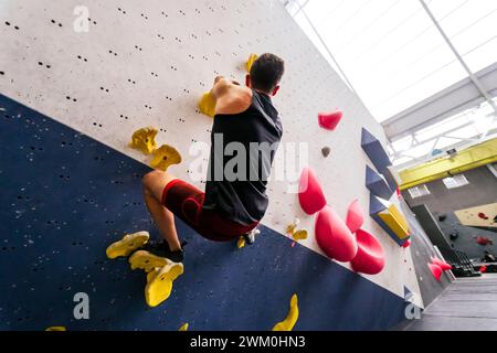 Athlète grimpant sur un mur de rochers Banque D'Images