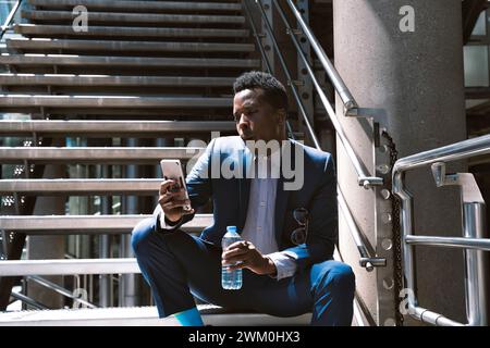 Homme d'affaires mature utilisant le téléphone mobile sur les étapes Banque D'Images