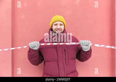 Homme heureux tenant du ruban barricade rouge et blanc devant le mur de pêche Banque D'Images