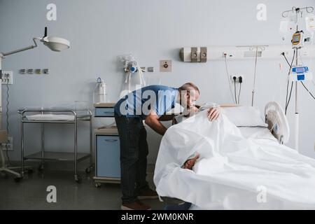 Homme embrassant femme couchée sur le lit à l'hôpital Banque D'Images