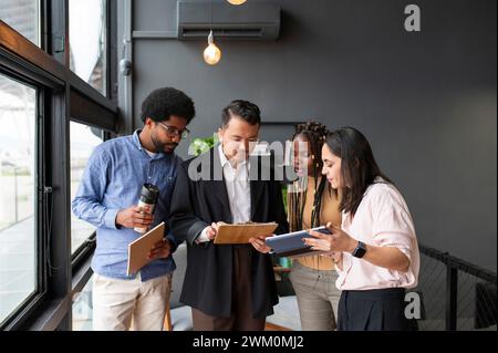 Hommes d'affaires et femmes d'affaires discutant sur presse-papiers dans le bureau Banque D'Images