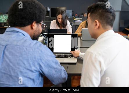Hommes d'affaires discutant sur ordinateur portable près des femmes d'affaires travaillant au bureau Banque D'Images