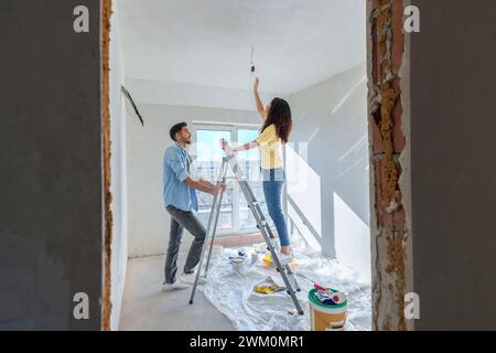 Jeune couple installant l'ampoule à la nouvelle maison Banque D'Images