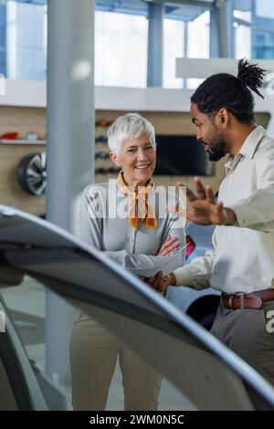 Vendeur montrant la voiture à un client satisfait dans la salle d'exposition Banque D'Images