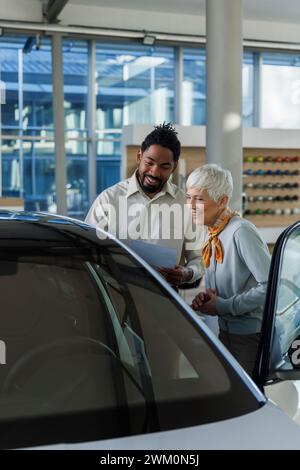 Vendeur heureux montrant la voiture au client dans la salle d'exposition Banque D'Images