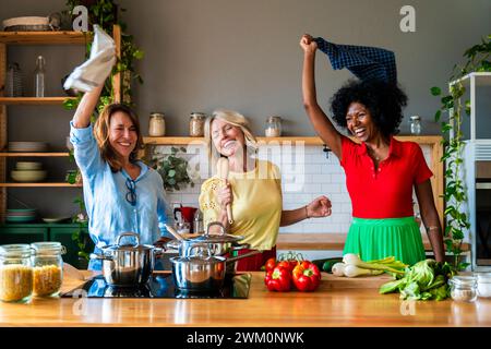 Amis joyeux s'amusant dans la cuisine à la maison Banque D'Images