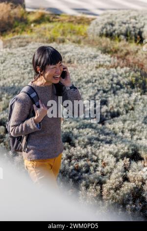 Femme heureuse parlant au téléphone portable près des plantes Banque D'Images