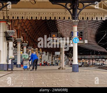 Une plate-forme de gare, bordée de colonnes, courbes, dans un hall principal. Une canopée historique du XIXe siècle est au-dessus et un nettoyeur vide les ordures Banque D'Images