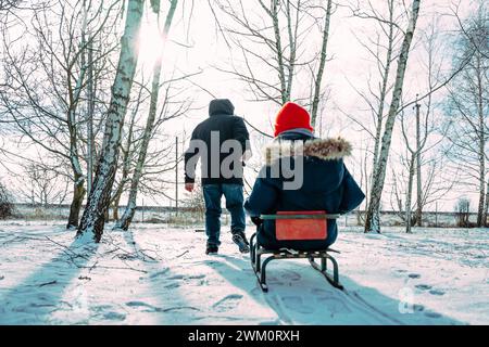Papa tirant son fils assis sur le traîneau en hiver Banque D'Images