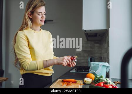 Jeune femme épluchant des légumes dans la cuisine à la maison Banque D'Images