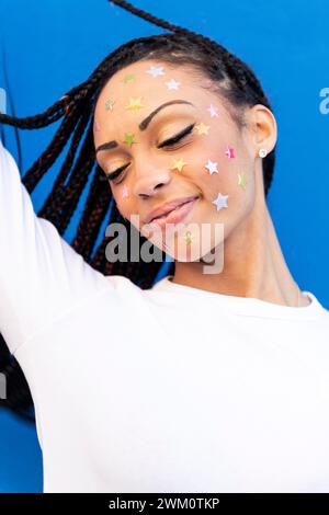 Femme souriante avec des cheveux tressés et des autocollants en forme d'étoile sur le visage Banque D'Images