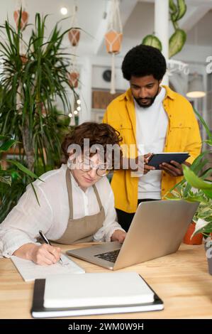 Botaniste et collègue travaillant ensemble en pépinière Banque D'Images