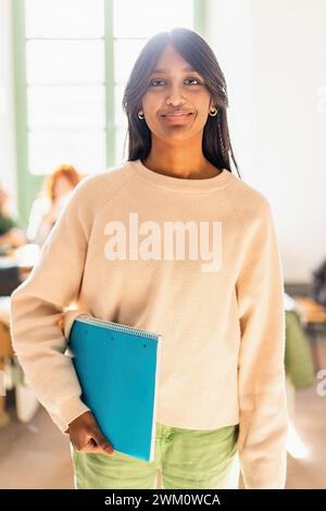 Jeune femme indienne confiante dans un environnement éducatif tenant un cahier - réussite académique et concept de diversité Banque D'Images