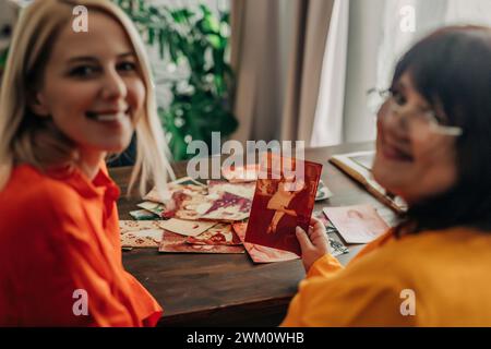 Mère et fille souriantes avec des photos de famille à table Banque D'Images