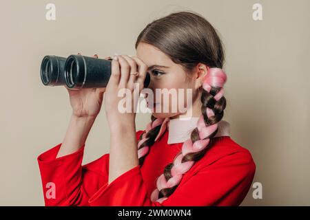 Femme regardant à travers des jumelles près du mur Banque D'Images