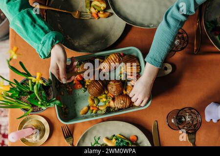 Famille ayant des pommes de terre fraîchement cuites au dîner de Pâques Banque D'Images