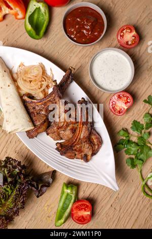 Un délicieux et copieux repas de côtelettes d'agneau grillées, de légumes et de pain lavash. Parfait pour un dîner en famille ou une fête entre amis. Banque D'Images