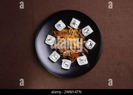 Cuisine japonaise, rouleaux de riz aux graines de sésame et sauce soja sur une assiette noire. Banque D'Images