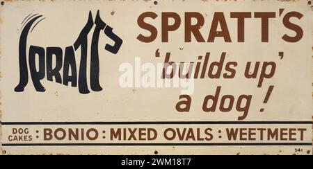 Émaux signe publicitaire des années 1930 Spratt's Dog Food. « Spratts construit un chien ». Belle illustration d'un chien terrier faite des lettres du nom spratts, logo de conception emblématique connu sous le nom de calligramme. Fabricants de Bonio, d'ovales mixtes et de Weetmeet. Les enseignes émaillées étaient fournies par les fabricants pour les fixer sur les façades des magasins afin de faire la publicité des marchandises. Fabriqués en métal, ils ont été conçus pour être robustes et durer longtemps, alors que les produits étaient maintenus en fabrication beaucoup plus longtemps qu’aujourd’hui. Aujourd'hui, ces enseignes en émail sont hautement collectionnables et même falsifiées. Banque D'Images