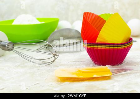 Gros plan des moules à cupcakes sur la table farinée, les ustensiles culinaires Banque D'Images