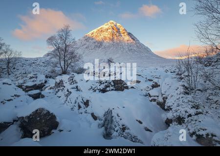 Une rivière de montagne gelée et une cascade au pied d'une montagne enneigée avec un pic ensoleillé le matin. Cascade Etive Mor. Scottish Highlands, Écosse Banque D'Images