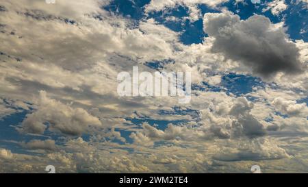 Vue expansive d'Un ciel bleu rempli de nuages de Cumulus blancs projetant des ombres les unes sur les autres sous la lumière du soleil. Banque D'Images