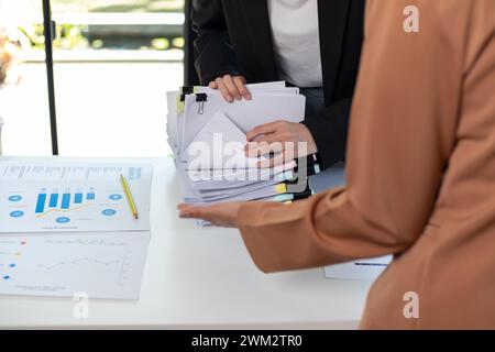 Un jeune secrétaire reçoit une pile de documents pour trouver des informations importantes pour le chef d'entreprise à utiliser lors d'une réunion. Le concept de recherche d'impor Banque D'Images