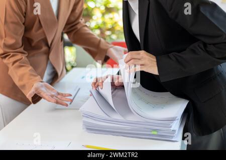 Un jeune secrétaire reçoit une pile de documents pour trouver des informations importantes pour le chef d'entreprise à utiliser lors d'une réunion. Le concept de recherche d'impor Banque D'Images