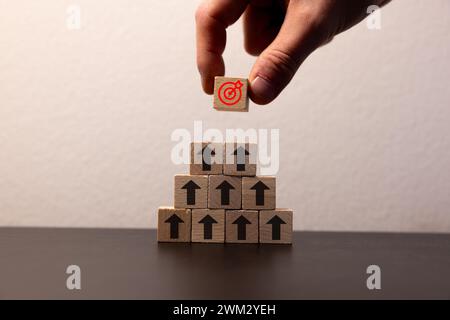 Main mettant la fléchette d'écran d'impression et le cube en bois de planche de cible sur les flèches vers le haut. Cible de l'investissement et concept d'entreprise. Banque D'Images