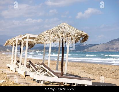 Crète sur la plage avec chaises longues, parasols typiques et mer Banque D'Images