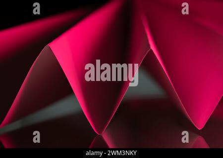 Perspective image abstraite de papier plié dans un motif plissé avec des reflets rouges sur une surface réfléchissante Banque D'Images