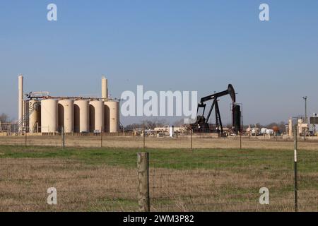 Réservoirs de stockage de puits de pétrole et cric de pompe à huile sur un socle de puits près de la ville de Falls City, Texas, États-Unis, le 23 février 2024. Falls City et le comté environnant de Karnes est l'un des 30 comtés qui composent la zone connue sous le nom de zone de production de pétrole et de gaz de schiste Eagle Ford. Récemment, la région autour de Falls City a connu une augmentation de l'activité sismique, y compris 23 tremblements de terre depuis le 11 février 2024. Les experts ont lié de nombreux tremblements de terre au Texas au processus d'extraction de pétrole et de gaz connu sous le nom de fracturation hydraulique. (Photo de Carlos Kosienski/Sipa USA) Banque D'Images