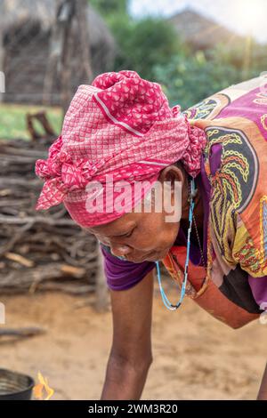 portrait d'une vieille femme de village africaine dans la cuisine extérieure cuisinant sur une casserole en étain Banque D'Images