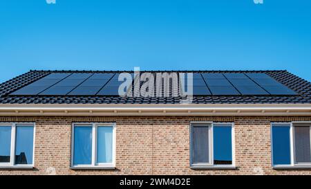 Un bâtiment rectangulaire avec des panneaux solaires sur le toit dans un quartier résidentiel. Les luminaires bleu ciel et Azur complètent le revêtement Banque D'Images