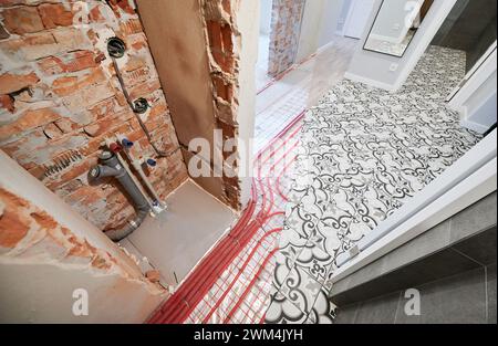 Comparaison des toilettes avant et après rénovation. Ancienne chambre d'appartement avec tuyaux de chauffage par le sol et nouvelle chambre rénovée. Banque D'Images