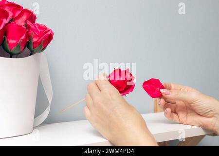 la main d'une femme déchire un pétale d'une rose. bouquet de roses artificielles. bouquet de roses en savon. pétales de rose rouge. Banque D'Images