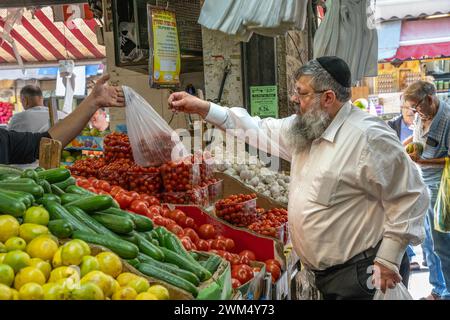 Jérusalem, Israël - 17 octobre 2023 : un homme juif orthodoxe achète des légumes au marché Mahane Yehuda, Jérusalem, Israël. Banque D'Images