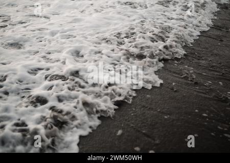 Ondulation de vagues sur un sable noir Banque D'Images