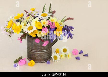 Arrangement de fleurs sauvages et d'herbes printanières de Beltane dans un vase vieux en étain sur papier de chanvre. Composition de fleurs de prairie britannique et de bois avec des fleurs aussi Banque D'Images