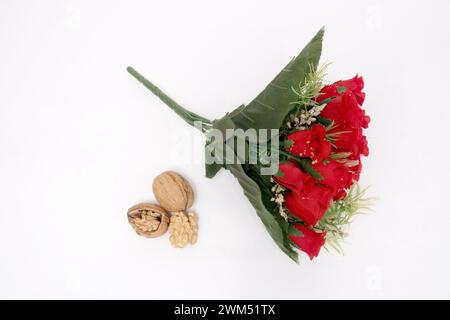 Élégantes roses rouges et noix fraîches : un mélange de beauté naturelle et de nutrition, Un bouquet vibrant de roses rouges, accentué de feuilles vertes et de blanc Banque D'Images