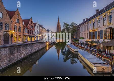 Canal illuminé dans la vieille ville de Bruges. Ambiance nocturne dans la ville hanséatique belge avec des bâtiments historiques et de vieilles maisons marchandes. Banque D'Images