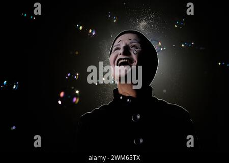 Portrait minimal de l'artiste mime excité debout dans des bulles de savon sur scène, espace de copie Banque D'Images