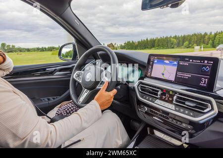 Vue rapprochée d'une femme au volant de la BMW iX3 M voiture électrique conduisant sur l'autoroute. Suède. Banque D'Images