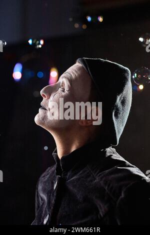 Vue latérale verticale portrait de mime artiste jouant avec des bulles de savon avec contre-jour Banque D'Images