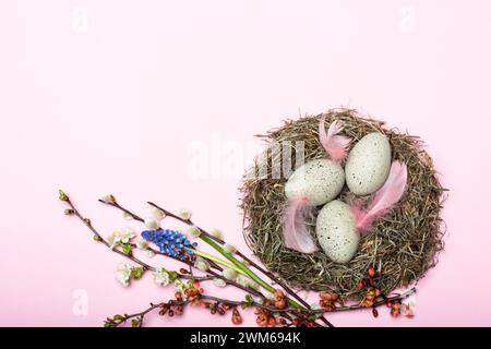 Nest mit gepunkteten Ostereiern und Blütendekoration vor pinkem Hintergrund Banque D'Images