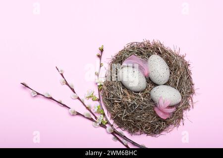 Nid mit gepunkteten Ostereiern und Blütendekoration vor pinkem Hintergrund *** nid avec des oeufs de Pâques en pointillés et des décorations florales sur fond rose Banque D'Images