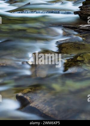 La paisible rivière Ljusnan serpente à travers le paysage accidenté de Härjedalen, son eau cascadant sur des rochers et des galets. La lumière tamisée et douce Banque D'Images