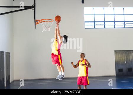 Un homme afro-américain entraîne un jeune homme biracial au basket-ball Banque D'Images