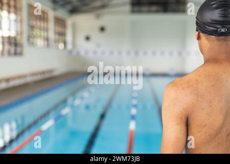 Jeune nageur athlète masculin biracial prêt à nager dans une piscine intérieure avec espace de copie Banque D'Images