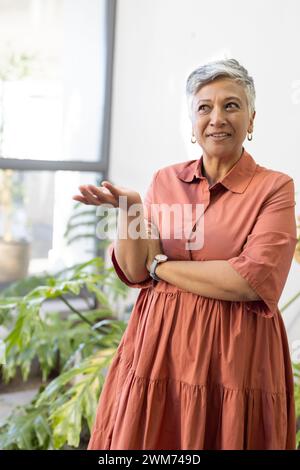 Femme biraciale senior se tient dans un espace lumineux à la maison Banque D'Images